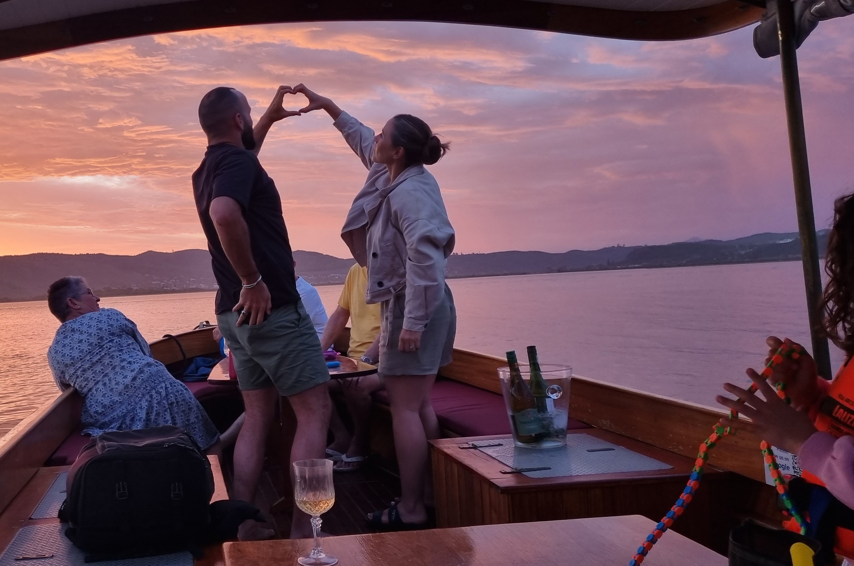 Coquette cruising on the Knysna Lagoon at golden hour with orange and golden sunset skies